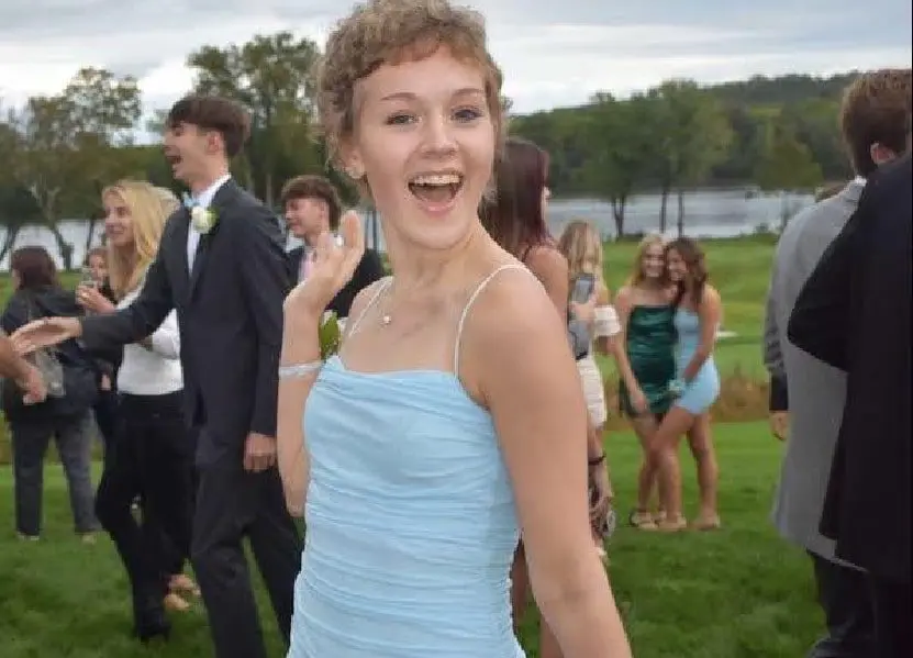 A girl in a blue dress is smiling for the camera.