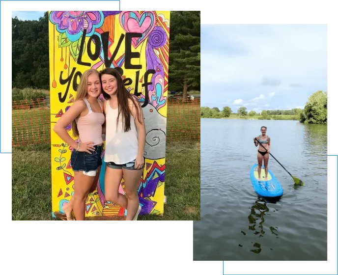 Two girls are standing in the water and one is on a paddle board.